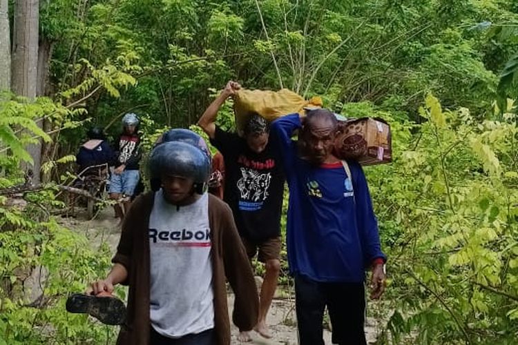 Para penumpang bus berjalan kaki sambil memikul barang akibat longsor yang menutup jalan Trans-Timor di Kupang, NTT