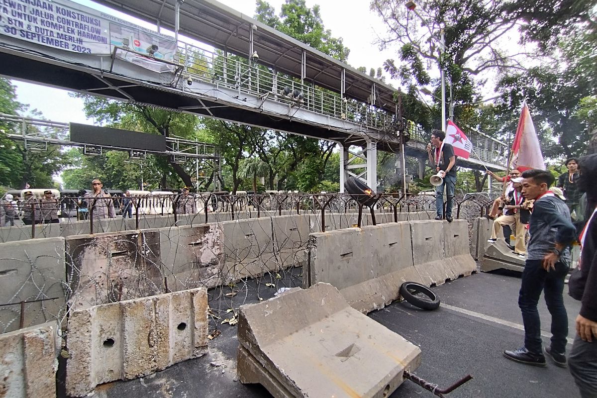 Mahasiswa menggulingkan beton pembatas saat unjuk rasa di kawasan Patung Kuda, Gambir, Jakarta Pusat, Jumat (20/10/2023) sore.