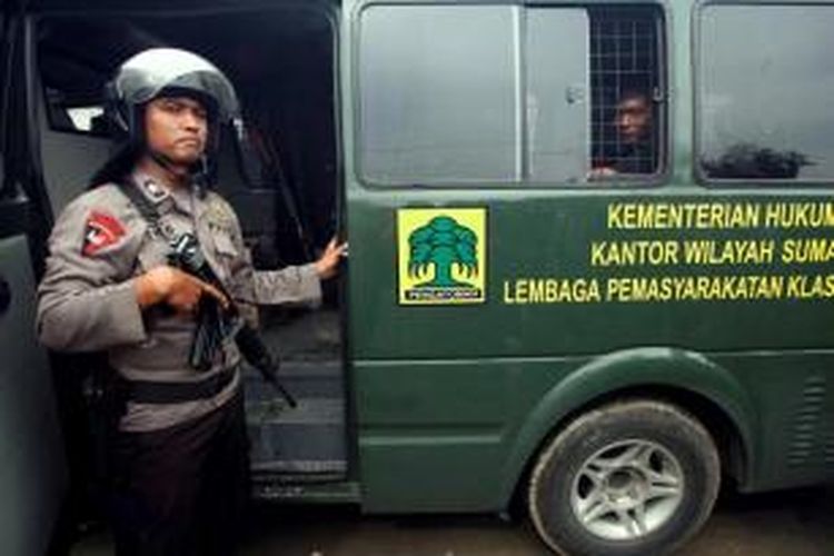 Polisi mengamankan proses pemindahan para narapidana pascakebakaran Lembaga Pemasyarakatan Kelas II A Labuhan Ruku di Kabupaten Batu Bara, Sumut, Senin (19/8/2013). Lapas dibakar saat kerusuhan antara sipir dan narapidana yang mengakibatkan 30 narapidana melarikan diri.