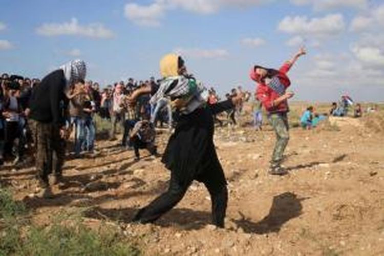 Perempuan Palestina bersama warga melempar batu ke arah tentara Israel dalam bentrokan yang terjadi di Jalur Gaza, 9 Oktober 2015.