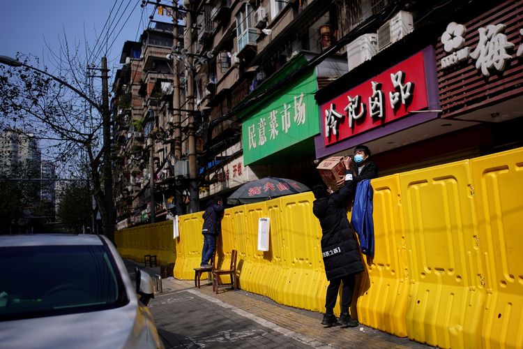 Pembeli membayar makanan melalui pagar pembatas di pasar basah Wuhan. Foto diambil pada 1 April 2020.