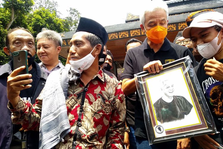 Gubernur Jawa Tengah Ganjar Pranowo menerima foto dari seorang pendukung di area Makam Bung Karno, Kota Blitar, Minggu (24/10/2021)