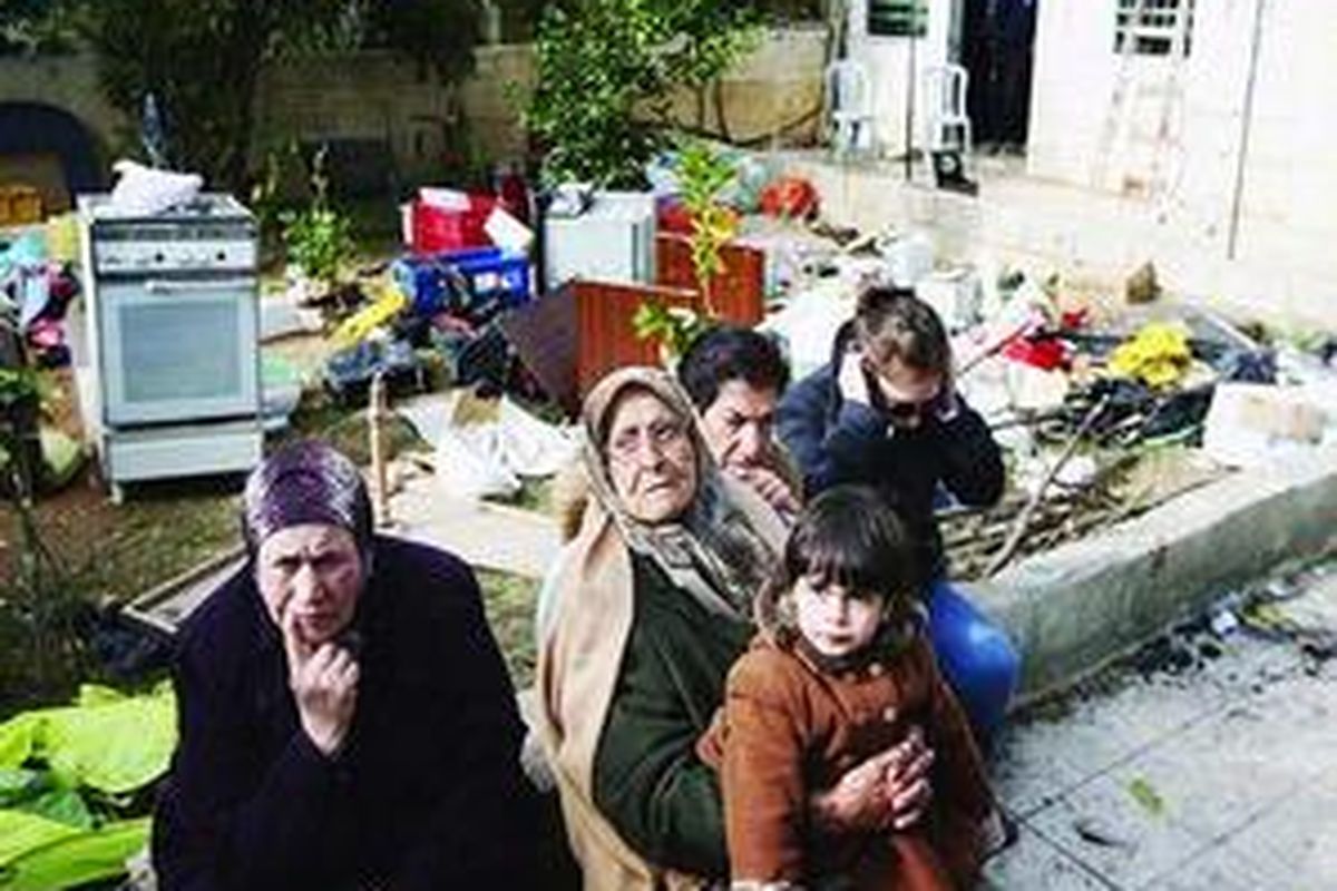 Anggota dari satu keluarga Palestina, yang rumahnya (ada di belakang) disita Yahudi, hanya bisa duduk termangu di depan eks rumah mereka di kompleks Arab di Sheikh Jarrah, Jerusalem Timur, Rabu (2/12).