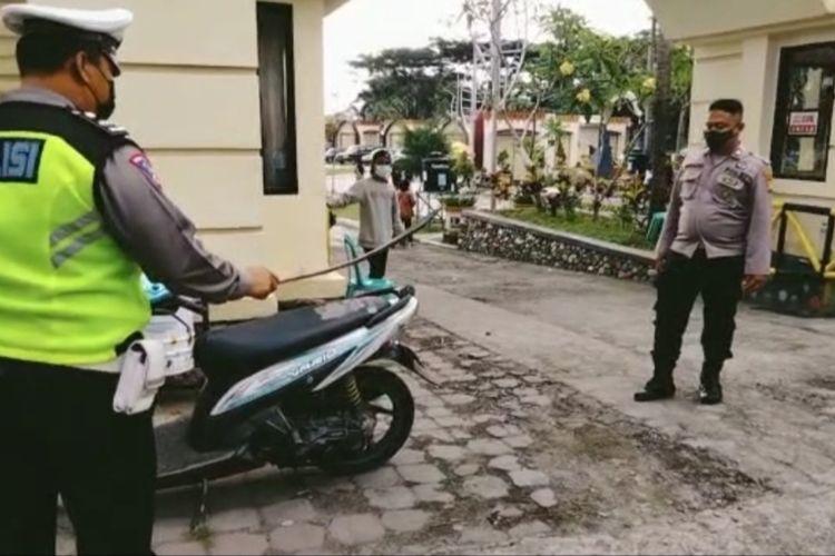 Anggota Kepolisian Polres Kota Mataram, Aipda Kadek Sudiarna.saat mengamankan ular dari sepeda motor milik seorang wisatawan lokal, Kamis (5/5/2022) di kawasan wisata Loang Baloq, Tanjung Karang Kita Mataram. Wisatawan itu tidak tahu jika saat berkendara ada ular melilit di bagian belakang sepeda motornya