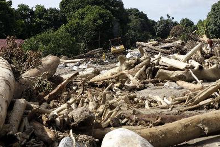 Sebuah alat berat, Senin (11/10/2010), digunakan untuk menyingkirkan batu dan kayu yang menutupi jalan di Kampung Rado, Kabupaten Teluk Wondama, Papua Barat. Akses di dalam kota dan ke luar kota tertimbun longsoran kayu, lumpur, dan batu akibat banjir bandang, 4 Oktober 2010.