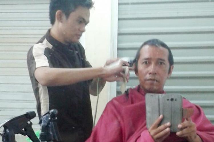 Bengbeng alias Bambang sedang mencukur pelanggan