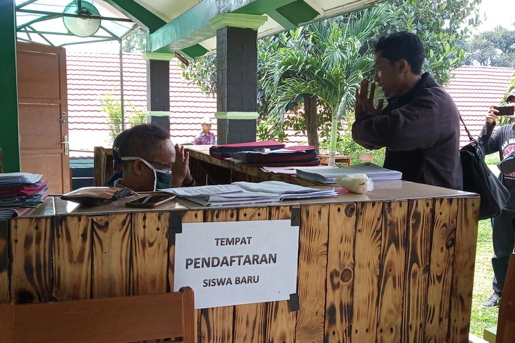 Seorang guru mendaftarkaj siswanya pada PPDB tahun ini di SMPN 2 Babakan Madang, Desa Bojong Koneng, Kabupaten Bogor, Jawa Barat.