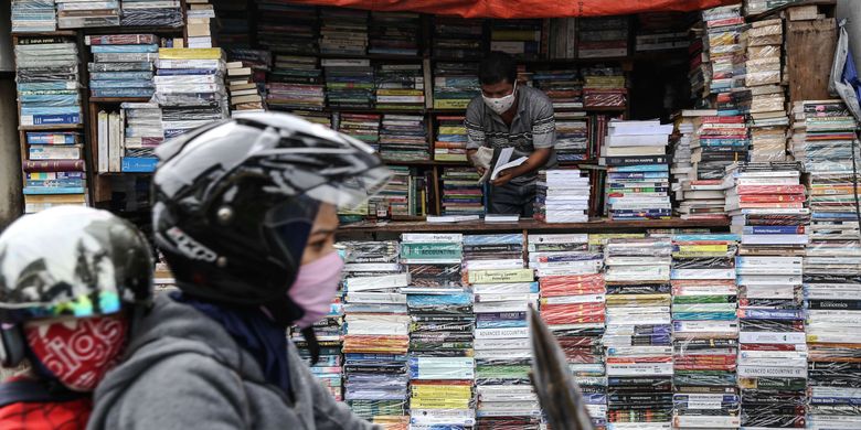 Warga menggunakan masker saat merapikan buku-buku di Jl. Letjen S. Parman, Jakarta Barat, Senin (4/5/2020). Provinsi DKI Jakarta memasuki pelaksanaan pembatasan sosial berskala besar (PSBB) yang diperpanjang ke tahap kedua. Tujuan PSBB ini adalah untuk menekan penyebaran virus corona (Covid-19).