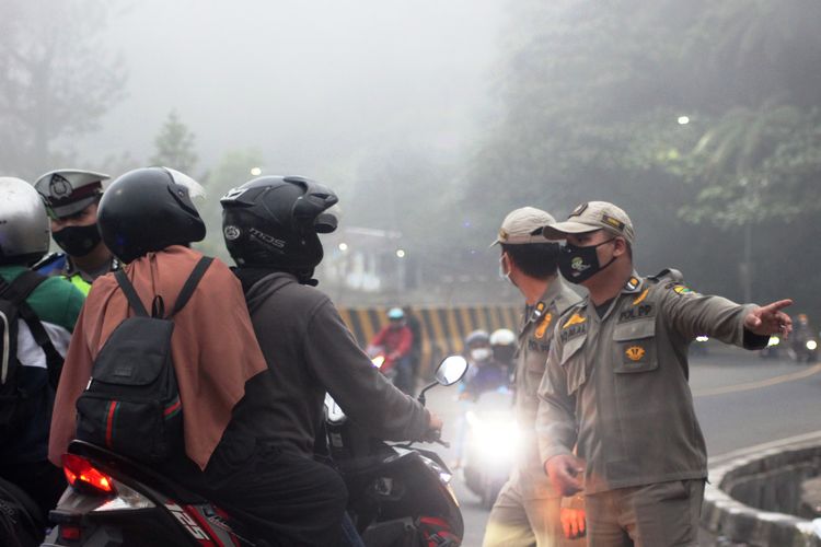 Petugas gabungan memutar balik kendaraan dari arah Bogor yang hendak menuju Cianjur di wilayah perbatasan Puncak Pass, Cianjur, Jawa Barat, Minggu (16/5/2021).