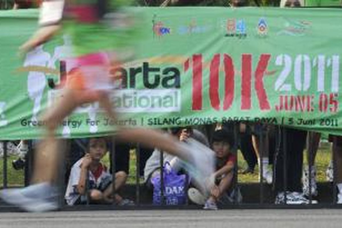 Warga melihat peserta lomba lari Jakarta International 10K 2011 yang akan memasuki garis finish di kawasan Monumen Nasional, Jakarta, Minggu (5/6/2011). Lomba lari menempuh jarak 10 kilometer ini diadakan untuk merayakan HUT Ke-484 Kota Jakarta.