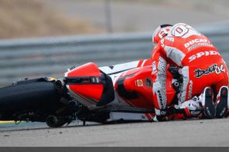 Pebalap Ducati asal Italia, Andrea Dovizioso, terduduk di dekat motornya setelah terjatuh saat membalap pada GP Jepang di Sirkuit Suzuka, Minggu (28/9/2014).