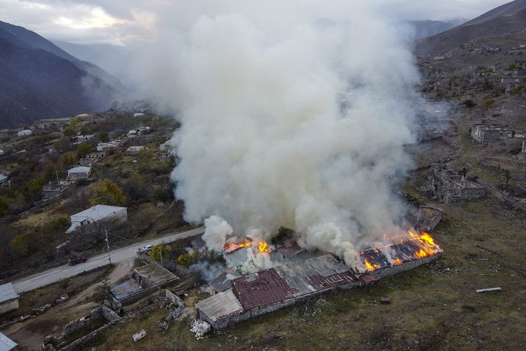 Asap membumbung dari sebuah rumah yang sengaja dibakar di Karvachar, wilayah separatis Nagorno-Karabakh, pada Jumat (13/11/2020). Berdasarkan kesepakatan damai antara Azerbaijan dan Armenia, beberapa wilayah yang dikuasai Armenia di wilayah Nagorno-Karabakh beralih ke Azerbaijan.