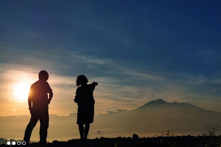 Dua orang wisatawan tengah menikmati pemandangan Gunung Gede Pangrango saat momen golden sunrise yang dilihat dari Desa Pasirjaya, Kecamatan Cigombong, Kabupaten Bogor pada Kamis (27/5/2021).