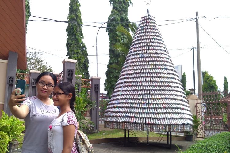 Salah satu umat berfoto dengan latar belakang pohon natal yang terbuat dari ecobrick di Gereja Katedral Krsitus Raja Purwokerto, Jawa Tengah.