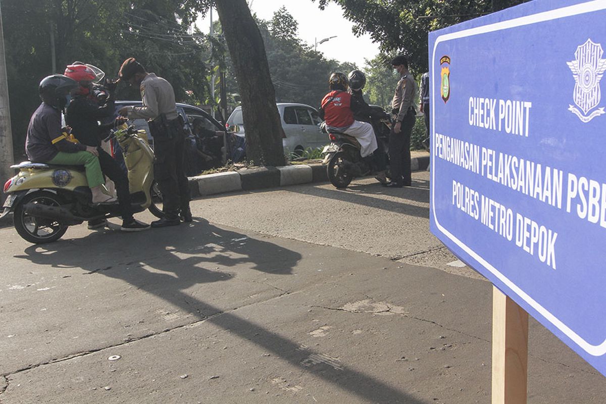 Petugas kepolisian memeriksa identitas pengendara motor yang berpenumpang saat penerapan PSBB di Perbatasan Jakarta - Depok, Depok, Jawa Barat, Rabu (15/4/2020). Pemeriksaan tersebut untuk memastikan setiap pengendara mematuhi aturan Pembatasan Sosial Berskala Besar (PSBB) yang diterapkan di Kota Depok.