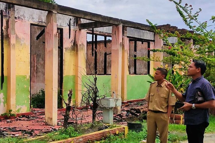 Kepala SMPN 1 Rambah, Irwan (kiri) memperlihatkan kondisi bangunan sekolah yang hangus terbakar belum diperbaiki hingga sekarang di Desa Koto Tinggi, Kecamatan Rambah, Kabupaten Rokan Hulu, Riau, Selasa (26/7/2022).
