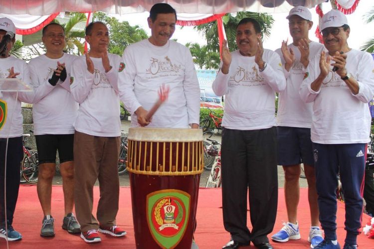 Menteri Koordinator Kemaritiman Luhut Binsar Panjaitan dan Gubernur Maluku, Said Assagaff, bersama puluhan peserta lomba balap Tour de Molvccas saat mengikuti balap sepeda keliling Kota Ambon, Minggu sore (17/9/2017) 