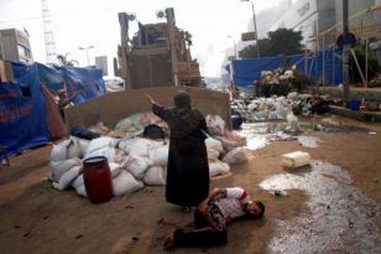 Seorang wanita Mesir mencoba untuk menghentikan buldoser militer yang akan menyakiti seorang pemuda terluka dalam bentrokan yang pecah ketika pasukan keamanan Mesir membubarkan pendukung Presiden Mesir terguling Muhammad Mursidi di kamp besar dekat Masjid Rabaa al-Adawiya di Kairo, 14 Agustus 2013.
