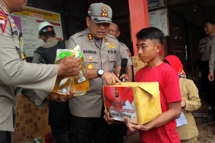 Kepala Polres Sukabumi AKBP Nasriadi (kiri) menyerakan bantuan sembako kepada waarga di Dusun Cimapag,. Desa Sirnaresmi, Kecamatan Cisolok, Sukabumi, Jawa Barat, Senin (7/1/2019)