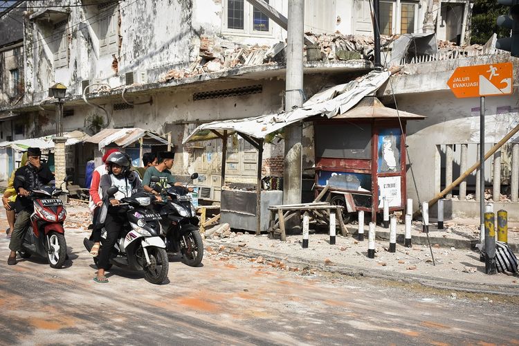 Sejumlah pengendara sepeda motor melintas dekat bangunan yang sebagian temboknya roboh akibat gempa susulan 6,2 SR di Ampenan, Mataram, NTB, Kamis (9/8). Pada Kamis (9/8/2018) pukul 13:25:32 WITA, gempa susulan dengan magnitudo 6,2 SR kembali mengguncang Lombok yang berpusat di Lombok Utara pada kedalaman 12 km getaran dirasakan di wilayah Lombok Utara,Mataram dan Lombok Tengah. ANTARA FOTO/Ahmad Subaidi/aww/18.