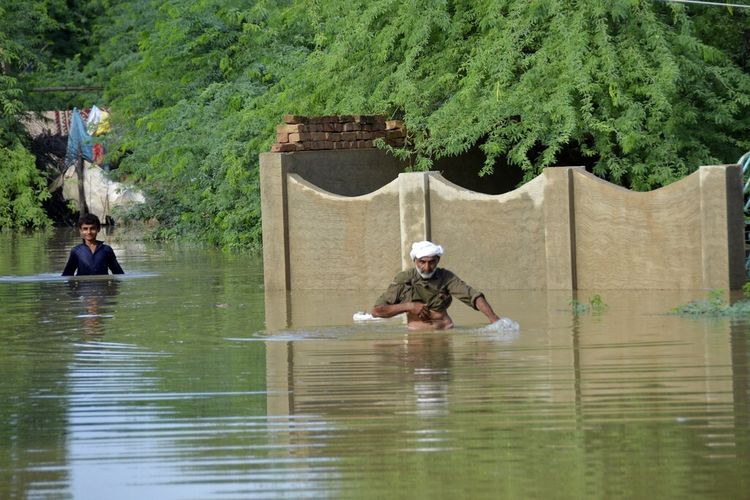 Orang-orang mengarungi daerah banjir Pakistan di Jaffarabad, distrik provinsi Baluchistan barat daya Pakistan, Jumat, 26 Agustus 2022.