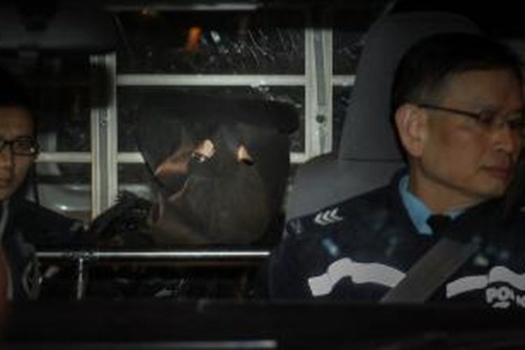 Majikan Erwiana Sulistyaningsih, Law Wan Tung (bertutup kepala), duduk di mobil polisi setelah ditangkap di bandara Hongkong, Senin (20/1/2014).