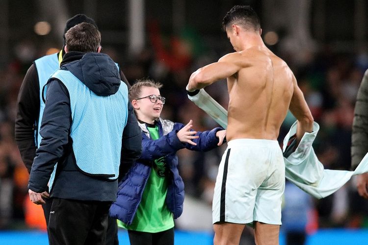 Penyerang timnas Portugal Cristiano Ronaldo memberikan jersey-nya kepada seorang fan cilik yang nekat masuk ke lapangan seusai laga lanjutan Kualifikasi Piala Dunia 2022 antara Portugal dan tuan rumah Republik Irlandia di Stadion Aviva, Dublin, Jumat (12/11/2021) dini hari WIB.