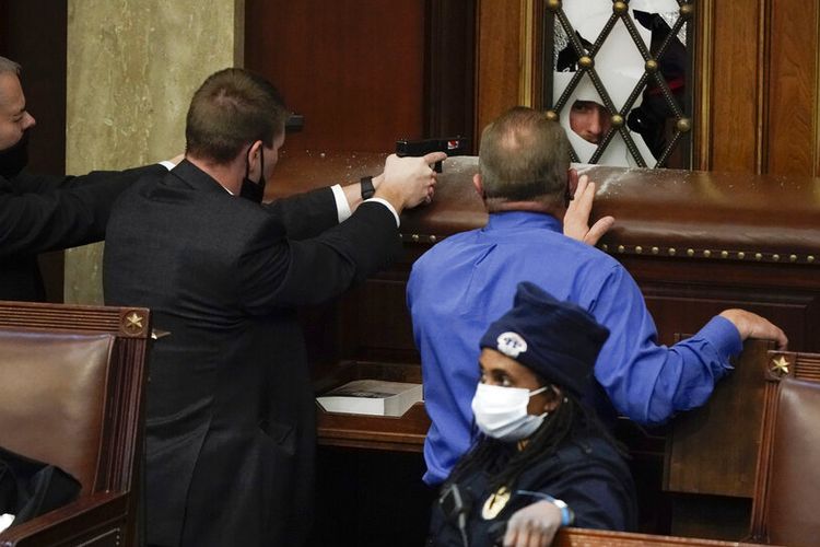 Lihat Foto Polisi dengan senjata ditarik berjaga-jaga ketika pengunjuk rasa mencoba masuk ke Ruang DPR di Capitol AS pada hari Rabu, 6 Januari 2021, di Washington.(AP PHOTO/ J SCOTT APPLEWHITE)
