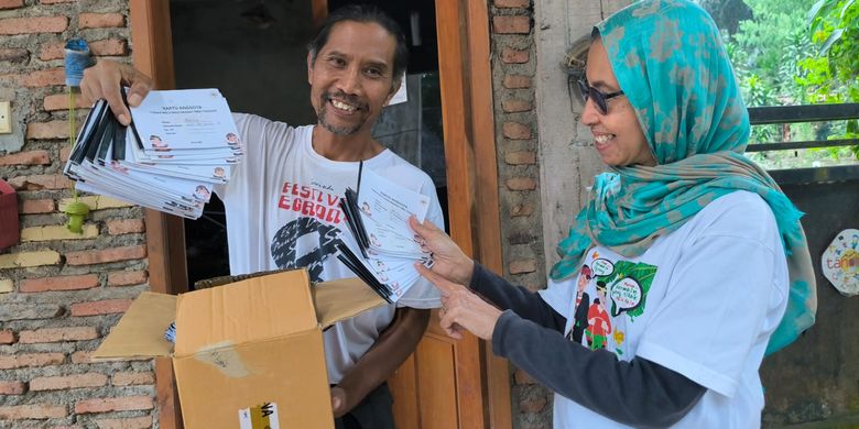Farha Ciciek dan Supoharjo menunjukkan kartu anggota perpustakaan milik anak-anak di Tanoker Ledokombo, Kabupaten Jember.