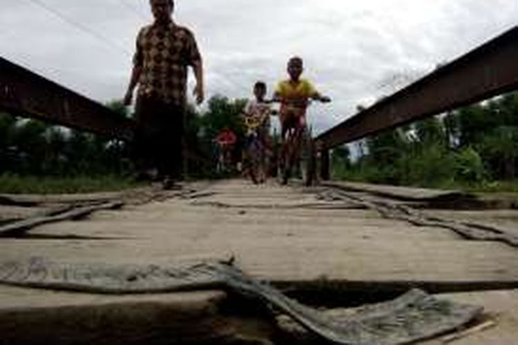 Warga melintasi jembatan kayu di Desa Bakalrejo,  Kecamatan Guntur,  Demak,  yang kondisinya memprihatinkan dan membahayakan keselamatan warga,  Rabu (12/10/2016 )