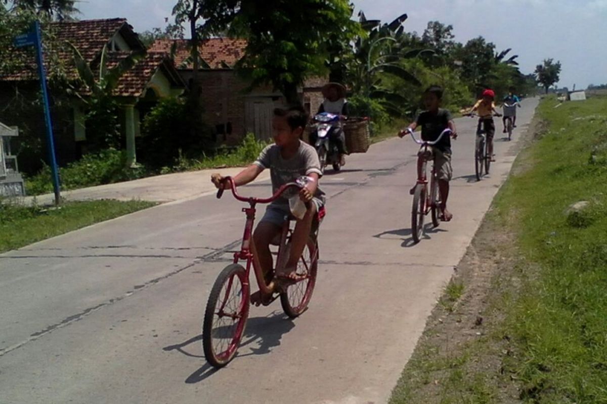 Anak - anak bermain sepeda di ruas jalan Karanganyar - Dempet,  Kabupaten Demak Jateng,  yang dibangun Pemkab Demak dengan cor beton, Sabtu (25/3/2017) 