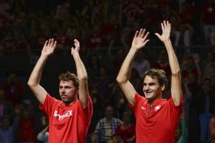 Petenis Swiss Stanislas Wawrinka (kiri) dan Roger Federer melambaikan tangan ke penonton setelah memastikan diri lolos ke semifinal Davis Cup 2014. Kepastian tersebut didapat setelah Federer mengalahkan wakil Kazakhstan, Andrey Golubev, pada laga kelima perempat final di Jenewa, Minggu (6/4/2014). Federer menang 7-6 (0), 6-2, 6-3.