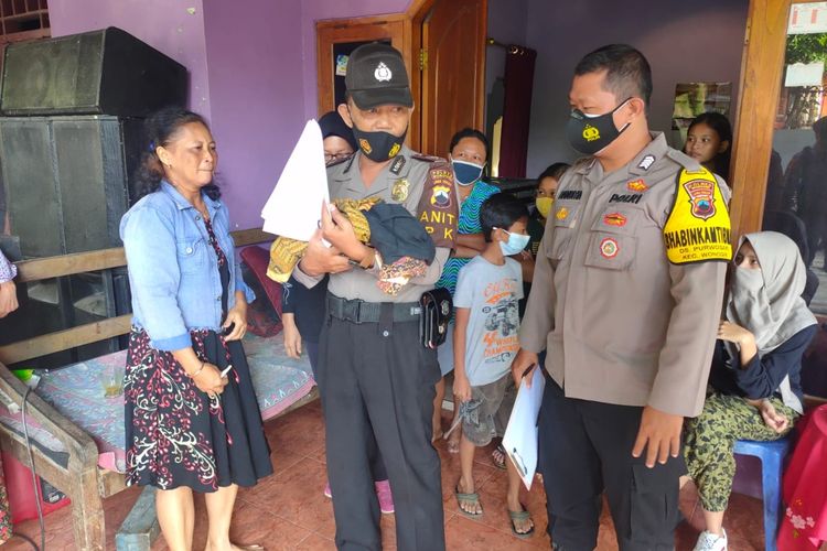 GENDONG--Salah satu anggota polisi menggendong bayi yang ditemukan dalam kardus dalam posisi mulut diplester di  Donoharjo, Kelurahan Wuryorejo, Kecamatan Wonogiri, Kabupaten Wonogiri, Jawa Tengah, Selasa (24/8/2021)