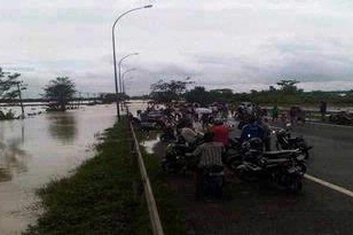 Warga berkerumun melihat ruas tol Tangerang-Merak yang tergenang banjir luapan Sungai Ciujung, Banten, Minggu (15/1/2012). 