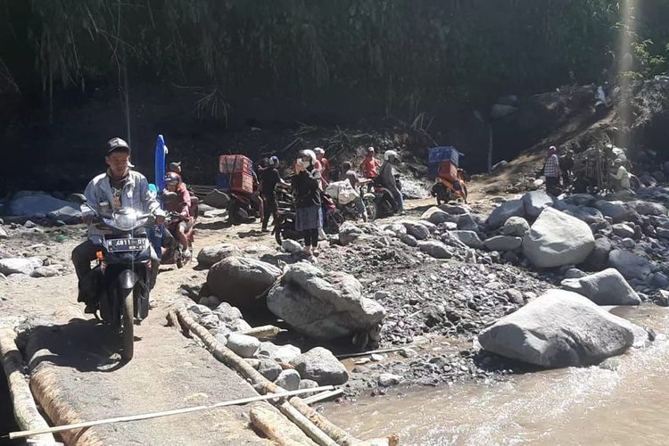 Warga melintasi jembatan darurat yang menghubungkan Malang dan Lumajang, Selasa (11/7/2023).