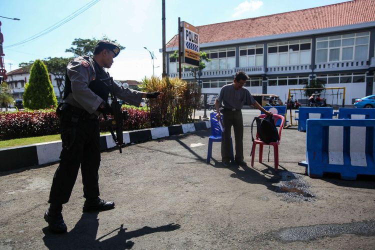 Petugas kepolisian memeriksa dokumen pengunjung di pintu masuk Polrestabes, Surabaya, Jawa Timur, Selasa (15/5/2018). Ledakan yang melukai empat anggota polisi dan enam warga terjadi pada Senin (14/5/2018) pagi di depan pos penjagaan pintu masuk Polrestabes Surabaya.