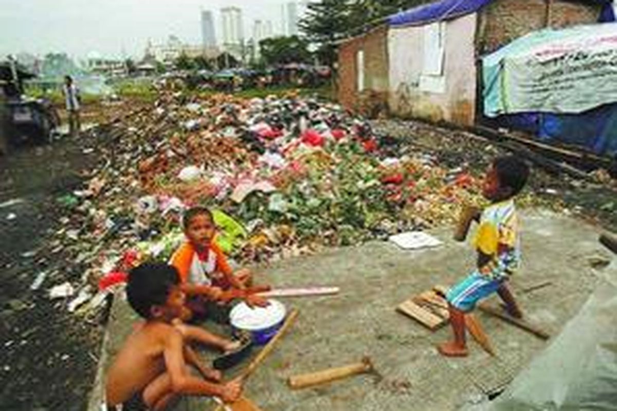 Anak-anak bermain musik di samping tumpukan sampah di pinggir Kali Banjir Kanal Barat, Tanah Abang, Jakarta Pusat, Rabu (19/11). Tumpukan sampah yang tidak terangkut dan genangan air hujan di sekitarnya membuat bermacam penyakit mudah menyerang warga. 