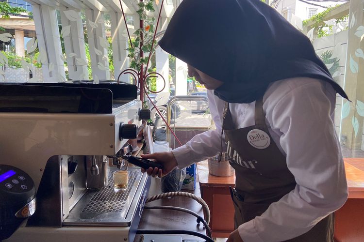 Della (20) barista tuli saat menyeduhkan kopi dari mesin di Kopi Tutur Rasa, Surabaya. 