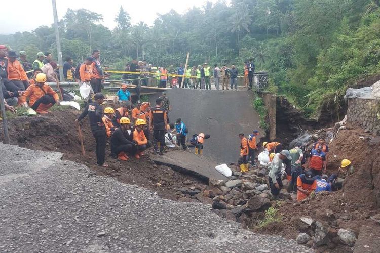 Petugas BPBD, Kepolisian, TNI dibantu warga sekitar sedang membongkar puing-puing jalan amblas akibat hujan deras di samping Jembatan Cidugaleun, Cigalontang, Kabupaten Tasikmalaya, Jawa Barat, Senin (8/5/2023).