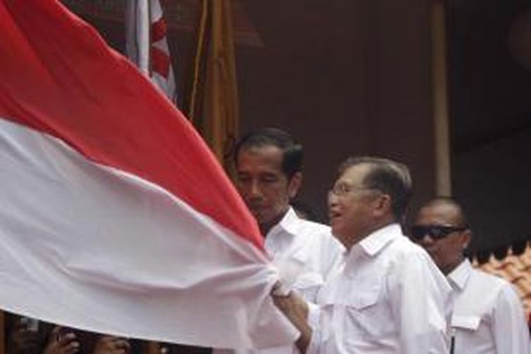 Joko Widodo dan Jusuf Kalla mencium bendera merah putih seusai deklarasi pasangan calon presiden dan calon wakil presiden di Gedung Joeang 45, Jakarta, 19 Mei 2014. PDIP bersama Partai Nasdem, PKB, dan Partai Hanura sepakat mengusung Joko Widodo dan Jusuf Kalla untuk maju sebagai pasangan capres dan cawapres.