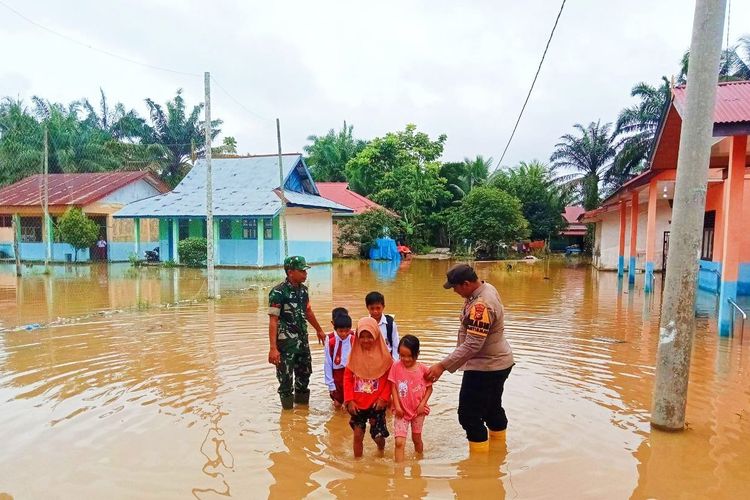 Petugas TNI dan Polri membantu anak-anak sekolah mengarungi banjir menuju sekolahnya di Desa Kasang Mungkal, Kecamatan Bonai Darussalam, Kabupaten Rokan Hulu, Riau, Selasa (5/12/2023).