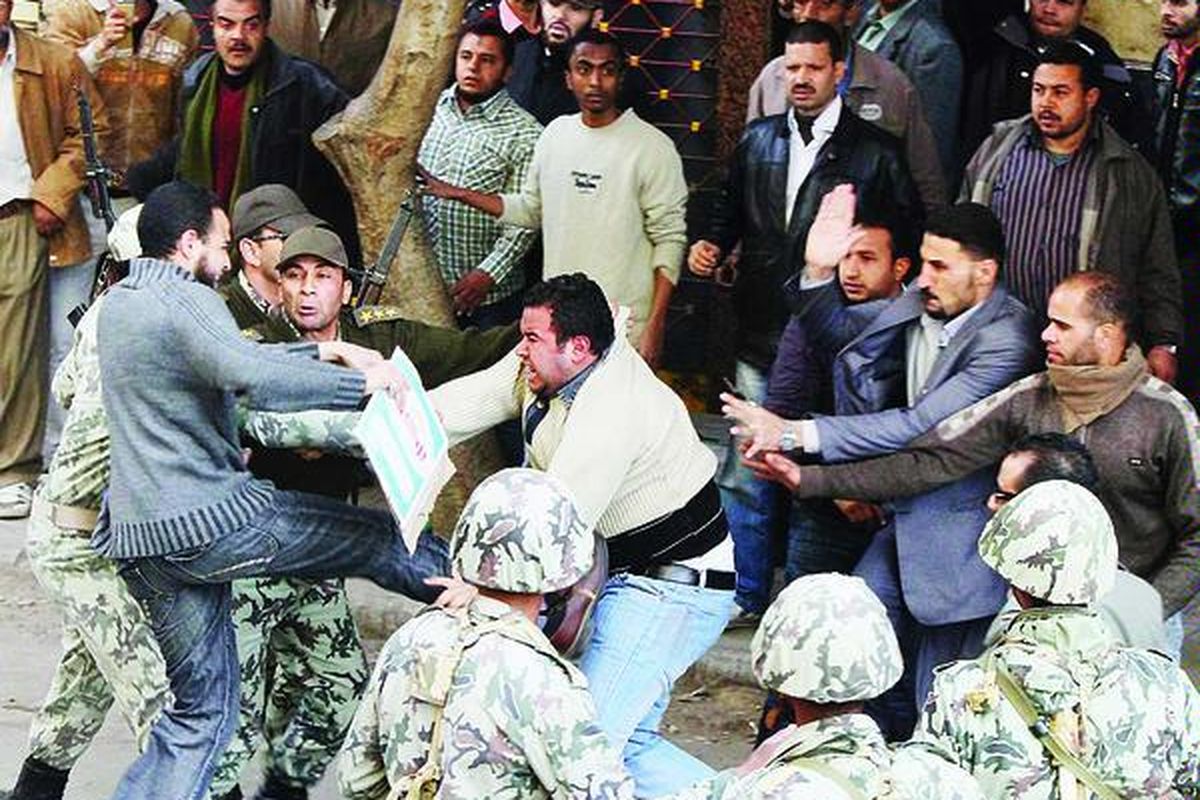 Tentara Mesir berupaya melindungi seorang warga sipil dari amukan pengunjuk rasa yang mencurigai lelaki itu adalah polisi yang berpakaian preman di Tahrir Square, Kairo, Mesir, Senin (31/1).