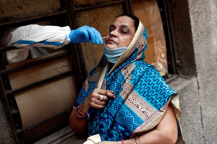 Seorang tenaga medis mengambil sampel dari seorang perempuan di sebuah sekolah yang diubah menjadi tempat untuk melakukan tes penyakit virus korona (COVID-19) di tengah penyebaran penyakit tersebut di New Delhi, India, Senin (22/6/2020).