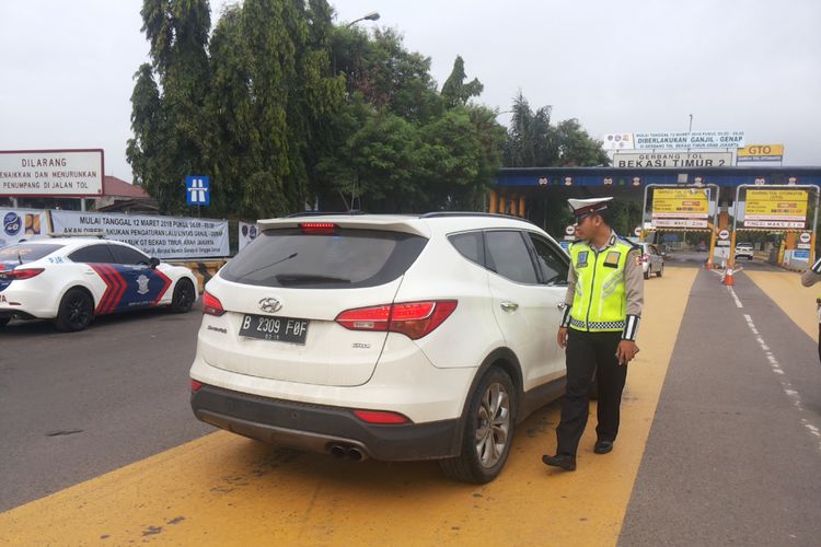 Salah satu mobil berpelat ganjil yang diminta putar balik di depan gerbang tol Bekasi Timur arah Jakarta pada hari pertama penerapan skema ganjil genap Tol Cikampek, Senin (12/3/2018).