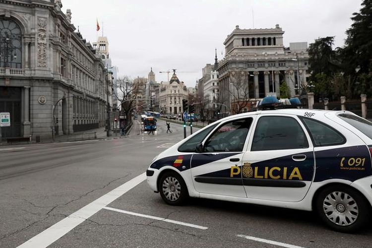 Sebuah mobil polisi berpatroli di Madrid, Spanyol, pada 20 Maret 2020, untuk memantau aktivitas warga dalam aturan lockdown yang diterapkan, terkait penyebaran virus corona yang meluas di Spanyol.