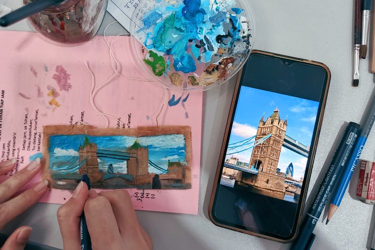 Salah satu Mahasiswa Ubaya sedang melukis menggunakan media kantong teh bekas untuk memperingati hari teh sedunia yang jatuh setiap tanggal 21 Mei.