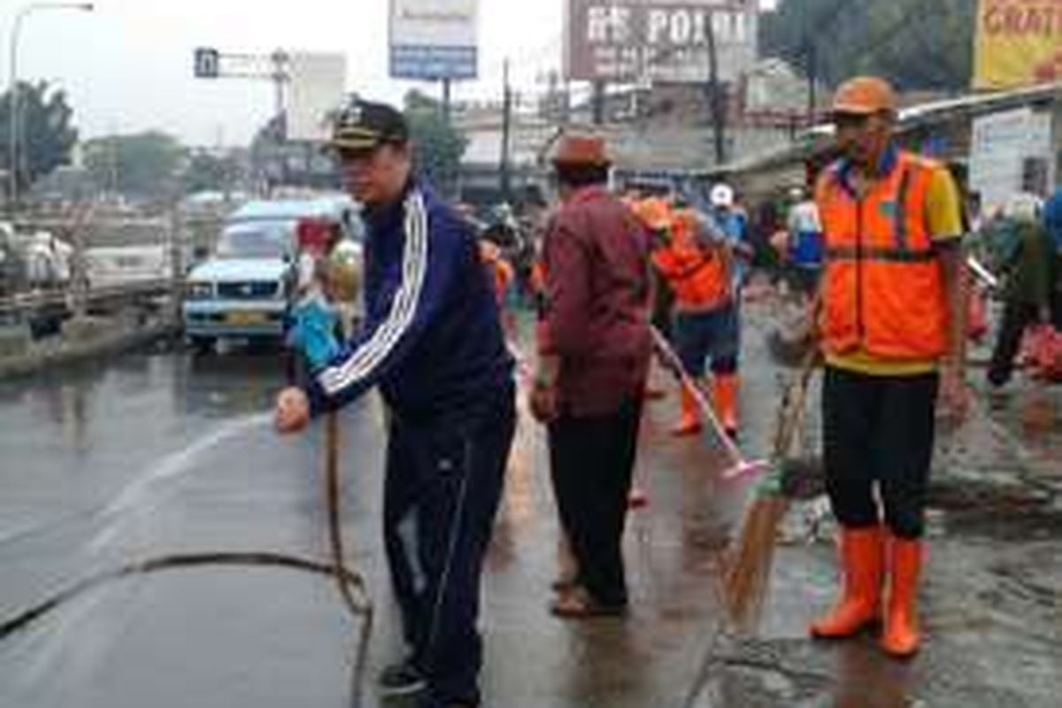 Jalan Raya Bogor disemprot karbol untuk menghilangan bau amis yang timbul dari sisa barang dagangan PKL.