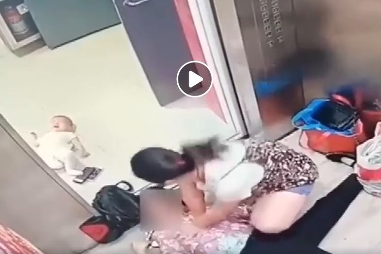 Seorang ibu muda tampak menolong seorang nenek yang pingsan di dalam lift.