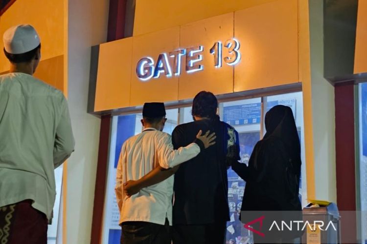 Beberapa orang berdoa di depan Gate 13 Stadion Kanjuruhan pada peringatan tiga tahun tragedi Kanjuruhan yang diselenggarakan di kawasan stadion di Kabupaten Malang, Jawa Timur, Rabu (1/10/2025) malam. 
