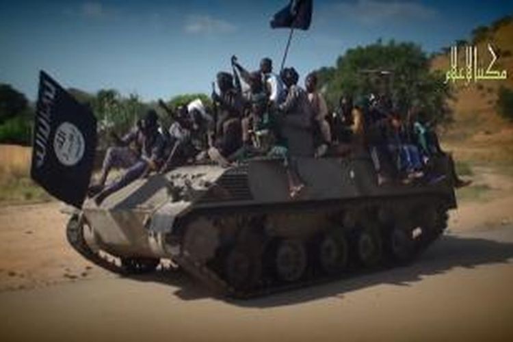 Dalam foto yang diambil dari sebuah video propaganda terlihat anggota Boko Haram menggunakan sebuah tank berparade di sebuah kota di Nigeria.